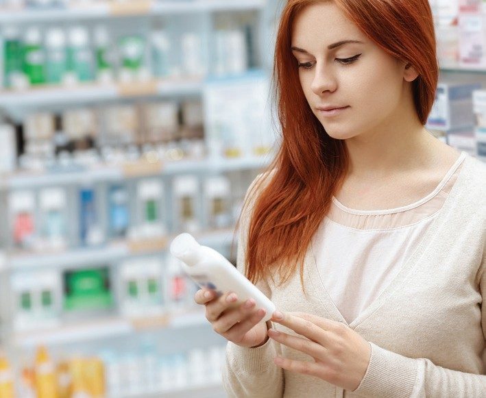 A customer examining a skincare product in a pharmacy