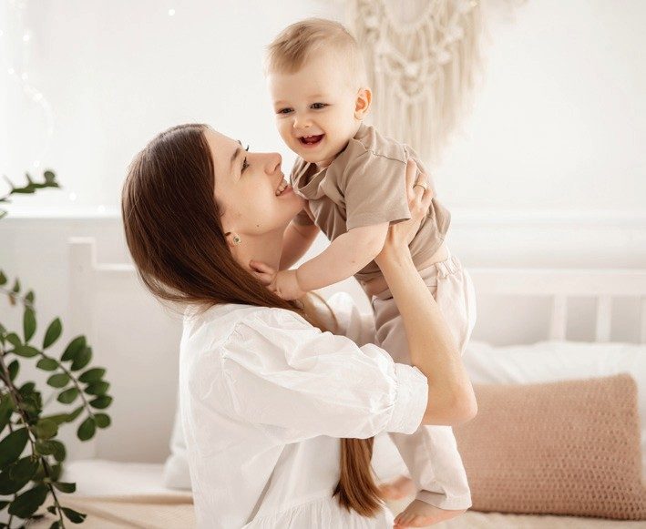 A mother holding her baby in a bright room