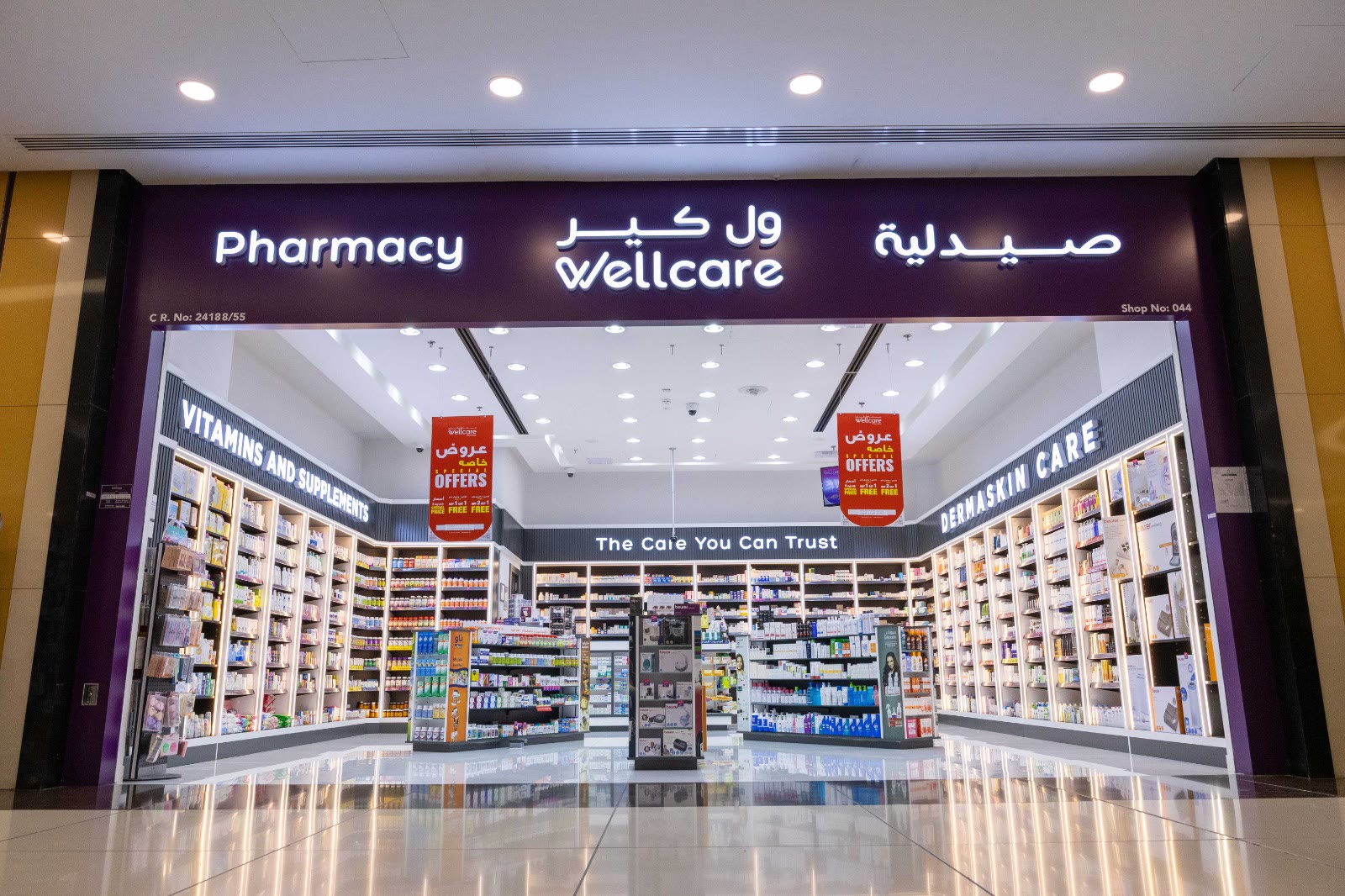 The Wellcare Pharmacy storefront with its illuminated purple bilingual sign